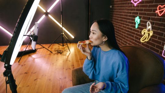 A woman in blue sweater eating a pizza